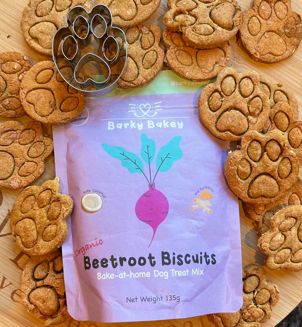 Pawprint cutter and embossed dog biscuits displayed with BarkyBakey Beetroot baking mix pouch on a flat lay background.