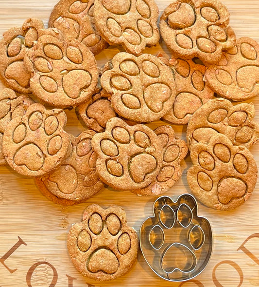 Pawprint cutter with baked dog biscuits showing embossed toe detail on a flat lay background.
